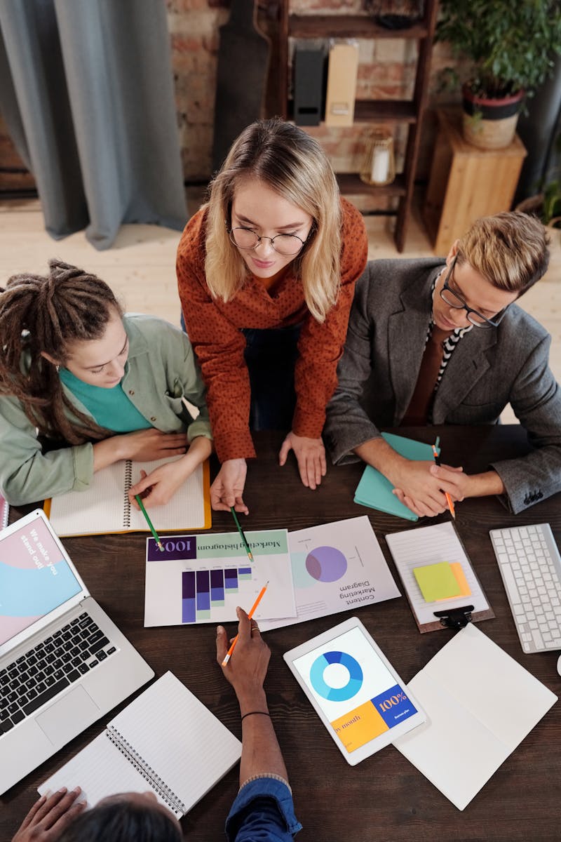 Top view of a diverse group discussing business reports and charts around a desk.